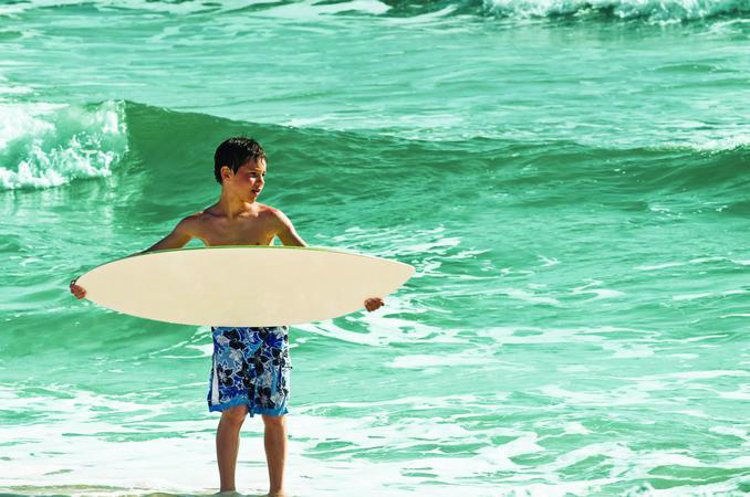 Boy with a boogie board enjoying the waves in Panama City Beach, FL